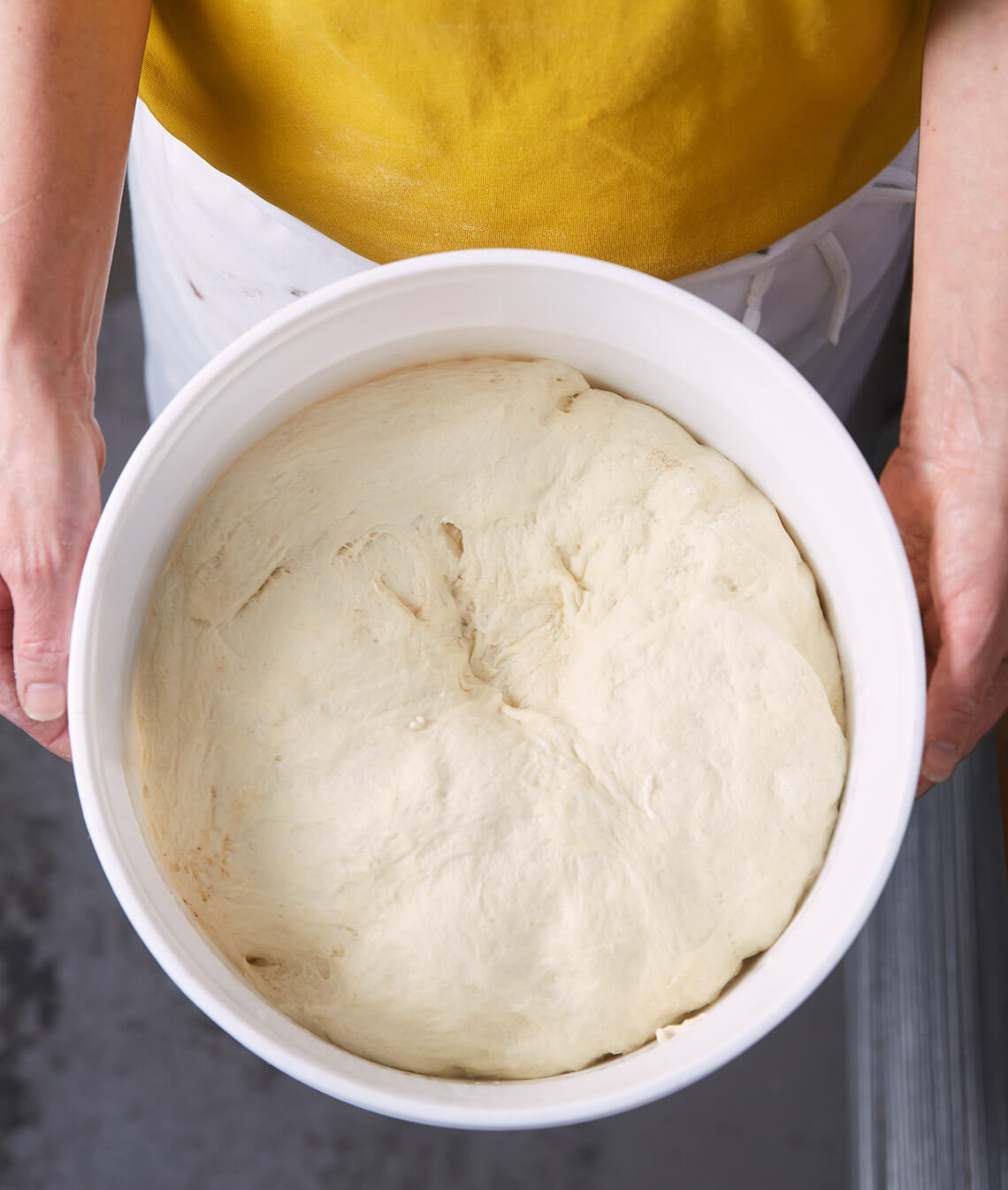 A baker holding a bucket of Mickey's decades-old starter dough