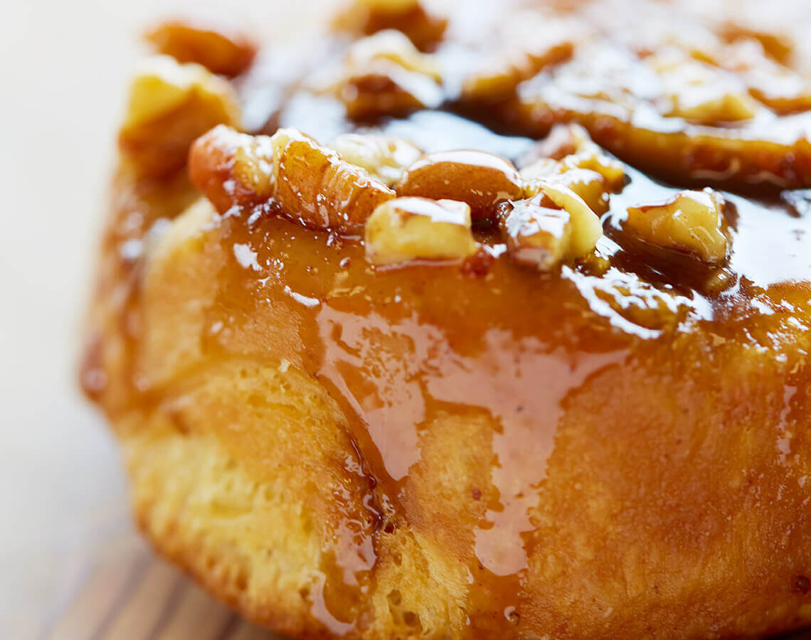 Close-up of a Mickey's sticky bun topped with caramel glaze and pecans